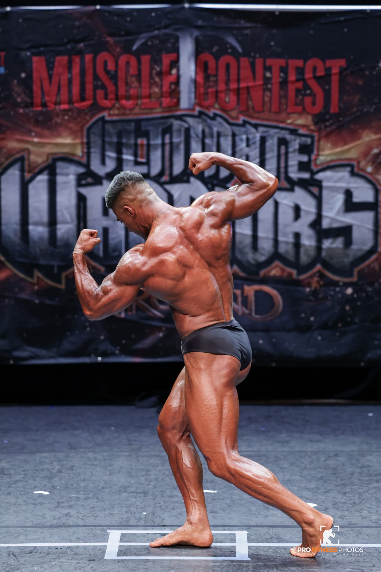 Coach M.M.X hitting a side triceps pose on stage at Ultimate Warriors Ireland