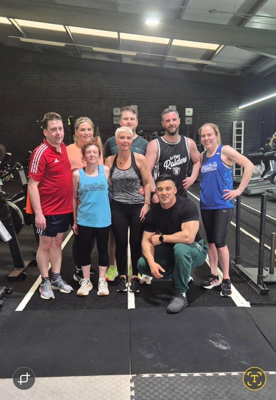 Coach M.M.X with a group of gym members after a class