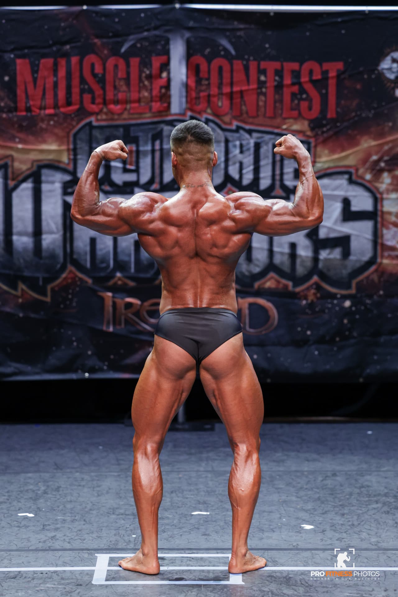 Coach M.M.X hitting a rear double biceps pose at Muscle Contest Ultimate Warriors Ireland