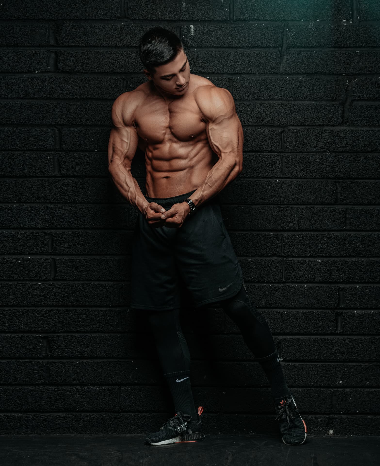 Coach M.M.X posing against a black brick wall showing conditioning