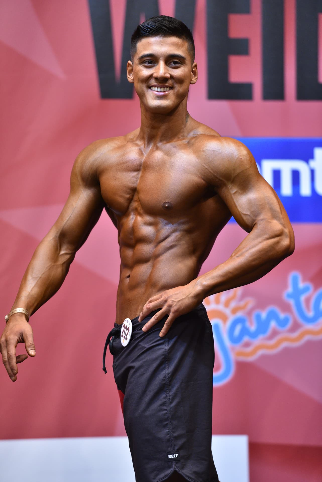 Coach M.M.X hitting a front pose on stage at a Weider competition