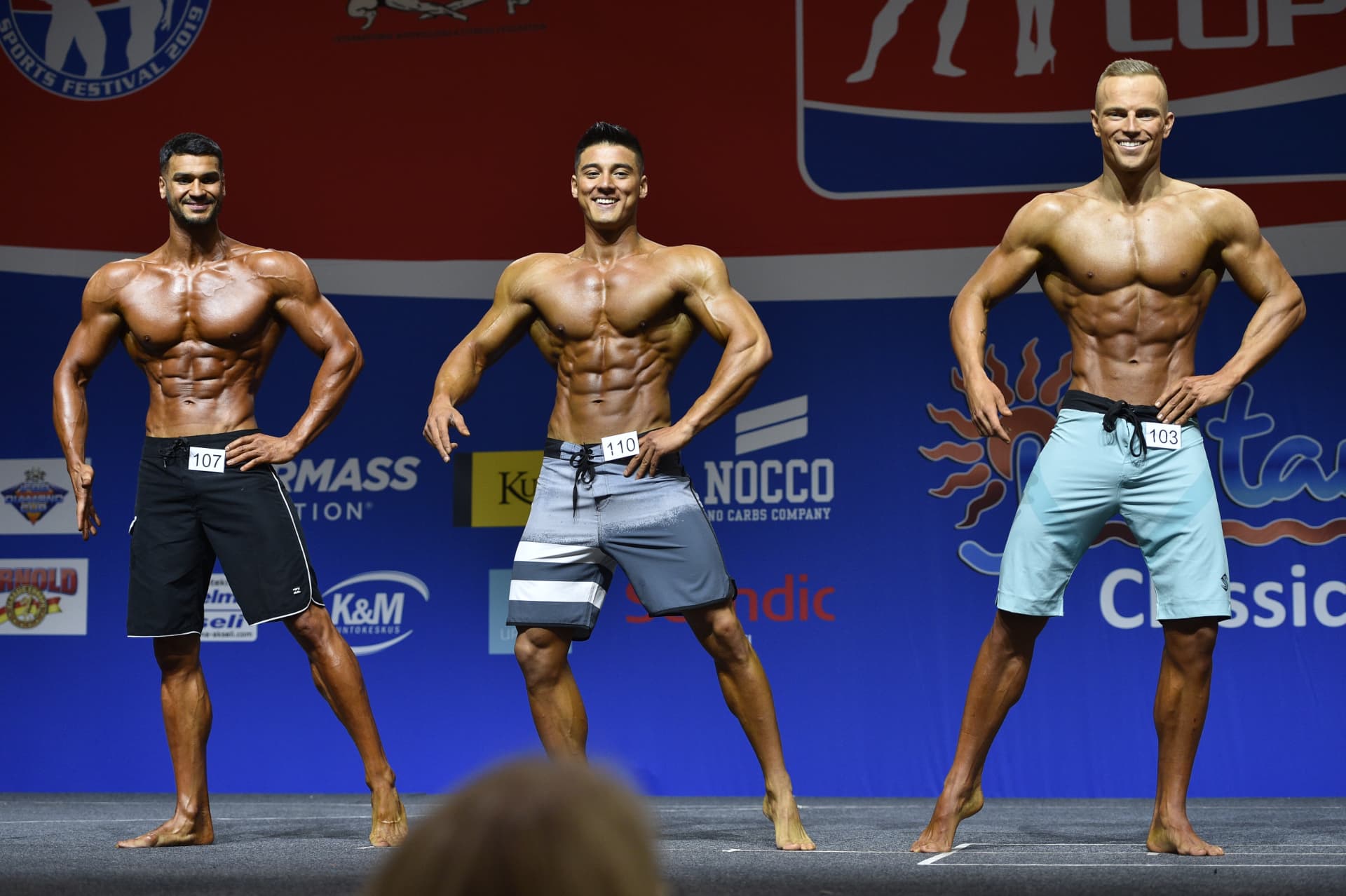 Men's physique comparison round on stage at an IFBB Diamond Cup event
